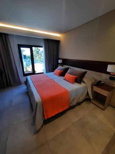 a bedroom with a large bed with an orange blanket at Hotel Estilo MB - Merlo in El Rincón