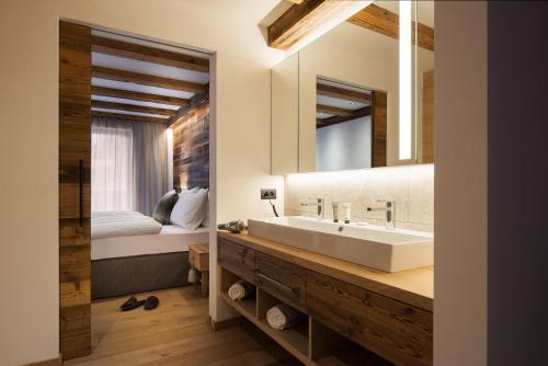 a bathroom with a sink and a bed and a mirror at K Lodge in Valdaora