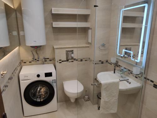 een kleine badkamer met een wasmachine en een wastafel bij Sun Coast Apartment in Sveti Vlas
