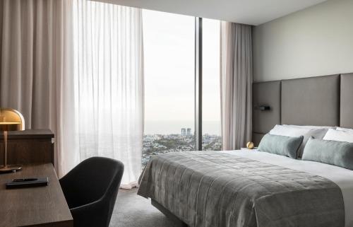 a bedroom with a bed and a desk and a large window at Oakwood Premier Melbourne in Melbourne