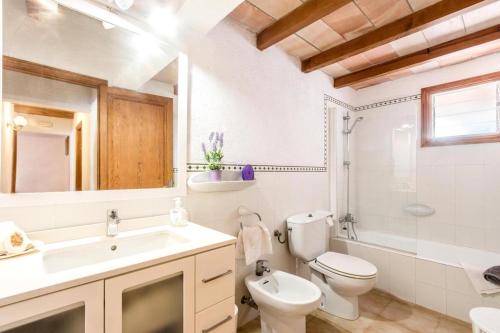 ein Badezimmer mit Waschbecken, Toilette und Spiegel in der Unterkunft Fontxica in El Port