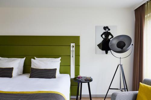 デュッセルドルフにあるホテル インディゴ デュッセルドルフ ヴィクトリアプラッツのベッドルーム1室(緑のヘッドボード付きのベッド1台付)