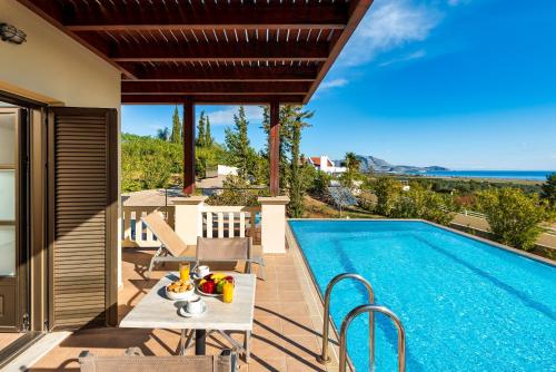 eine Villa mit einem Pool mit einem Tisch und Stühlen in der Unterkunft Aegean Blue Villa's - All Inclusive & Water park in Kalathos