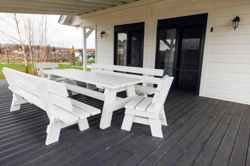a white picnic table and chairs on a porch at Dom Wakacyjny Baltic Home & Dom Baltic Home Garden Inn in Zastań