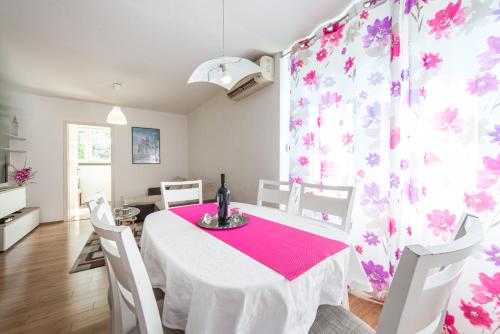 a dining room with a white table and pink curtains at Apartment Lidija in Dubrovnik