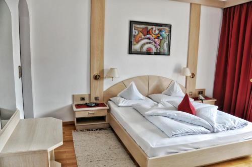 sypialnia z białym łóżkiem z czerwoną zasłoną w obiekcie Hotel Brunner w Meranie