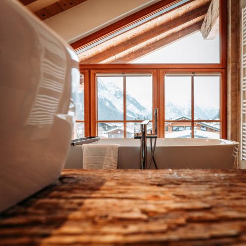 a room with a bath tub and a large window at IM WEIDACH Superior Chalets in Leutasch
