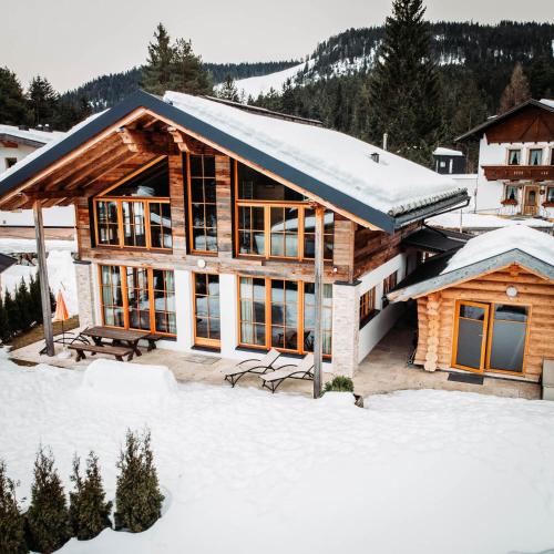 a log home with snow on the ground at IM WEIDACH Superior Chalets in Leutasch