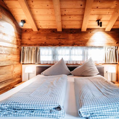 two beds in a room with wooden ceilings at IM WEIDACH Superior Chalets in Leutasch