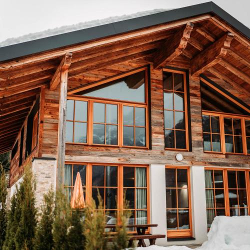 a log cabin with large windows and a picnic table at IM WEIDACH Superior Chalets in Leutasch