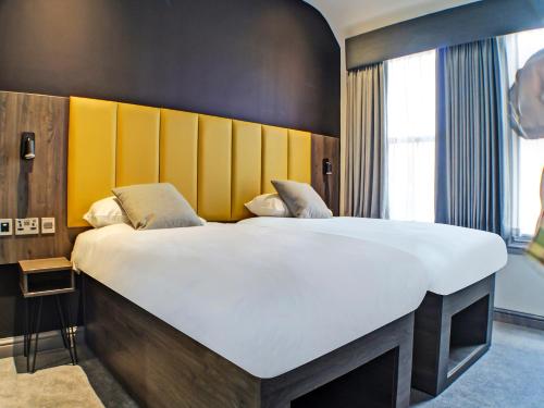 1 dormitorio con 1 cama grande y cabecero amarillo en OYO Tamworth Arms Boutique Pub & Hotel en Tamworth