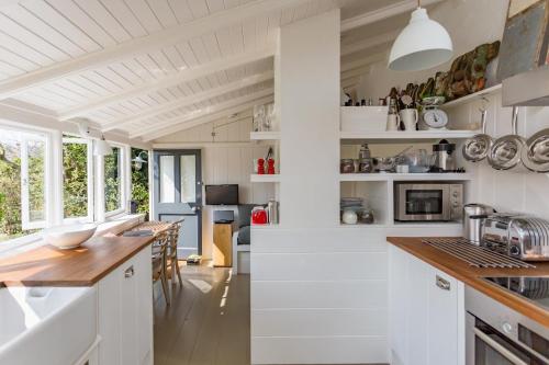 a kitchen with white cabinets and a wooden counter top at Antonia's Pearls in St Austell
