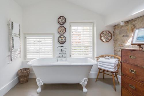 a white bath tub in a bathroom with two windows at Antonia's Pearls in St Austell