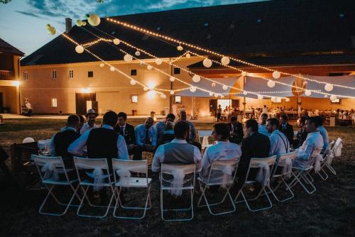 a group of people sitting in chairs under a tent at Zámecký Dvůr Černousy in V Poli