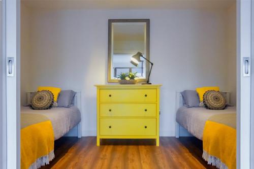 1 dormitorio con 2 camas y vestidor amarillo con espejo en The Nest en Youghal