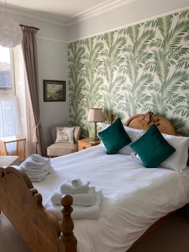ein Schlafzimmer mit einem großen weißen Bett mit grüner und weißer Tapete in der Unterkunft Thornsgill House Bed & Breakfast in Askrigg
