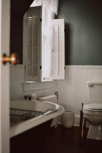 a white bathroom with a toilet and a sink at Hill Road Manor Bed & Breakfast in Grand Falls