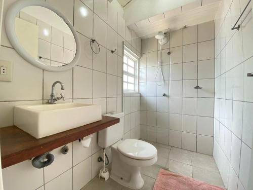 a bathroom with a sink and a toilet and a mirror at Casa Vento Leste in Ilhabela