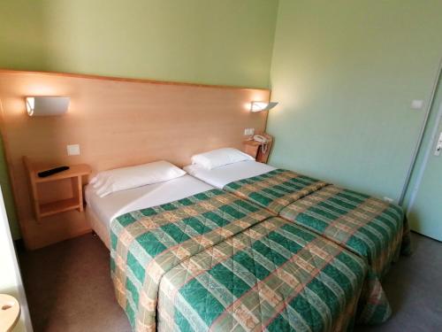 um quarto de hotel com uma cama com um cobertor verde em Les Charmilles em Poligny