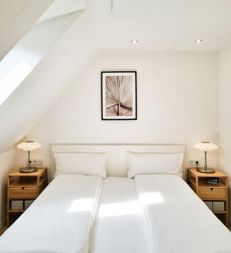 a bedroom with a white bed with two lamps at Mirielle Apartments in Rust
