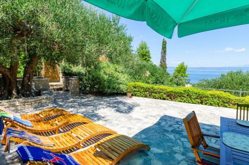 eine Gruppe Stühle und ein Sonnenschirm auf einer Terrasse in der Unterkunft Vacation House Marija, Korčula in Korčula