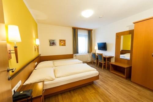 MürzhofenにあるGasthof Turmwirtのベッドとデスクが備わるホテルルームです。