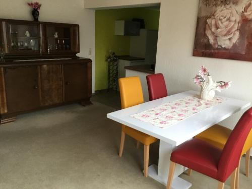 a dining room with a white table and colorful chairs at Haus Kim - Apartments in Waren