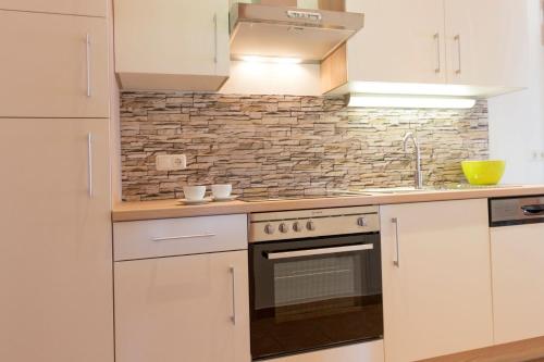 a kitchen with white cabinets and a stove top oven at Apart Chalet Unterbrandnerlehen in Schönau am Königssee