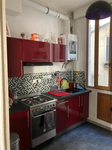 - une cuisine avec des placards rouges et une cuisinière dans l'établissement Appartement cœur de ville, à Avignon