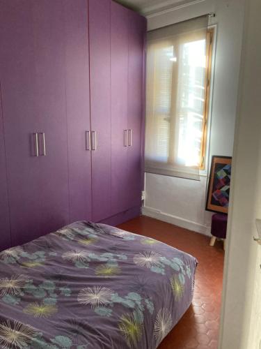アヴィニョンにあるAppartement cœur de villeの紫色のベッドルーム(ベッド1台、窓付)