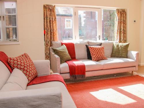 a living room with a couch and a window at Coach House at Old Vicarage in Telford