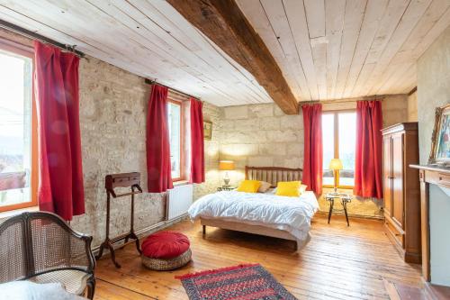 Schlafzimmer mit einem Bett und roten Vorhängen in der Unterkunft La Pierre Blanche 