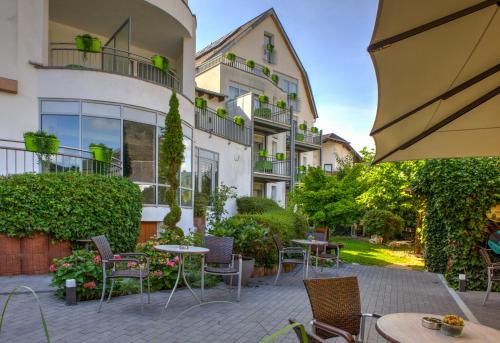 a patio with tables and chairs in front of a building at Moselromantik Hotel Am Panoramabogen in Cochem