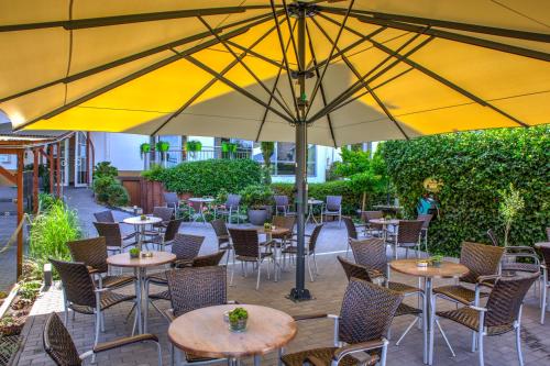 a patio with tables and chairs under a large yellow umbrella at Moselromantik Hotel Am Panoramabogen in Cochem