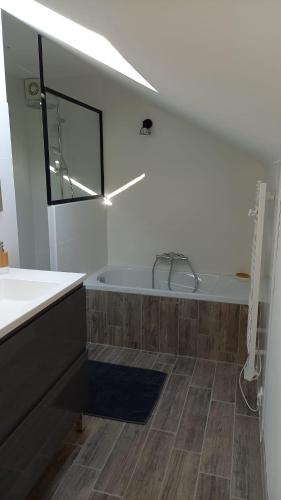La salle de bains est pourvue d'une baignoire et de parquet. dans l'établissement La Pause du Perche - gîte au pied de la forêt, à La Perrière
