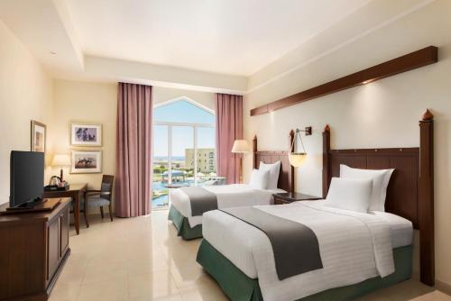 a hotel room with two beds and a television at Wyndham Garden Salalah Mirbat in Salalah