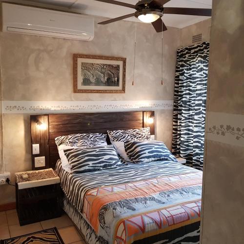 a bedroom with a bed and a ceiling fan at Matumi Self Catering in Marloth Park