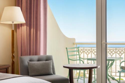 a room with a bed and a chair and a balcony at Wyndham Garden Salalah Mirbat in Salalah