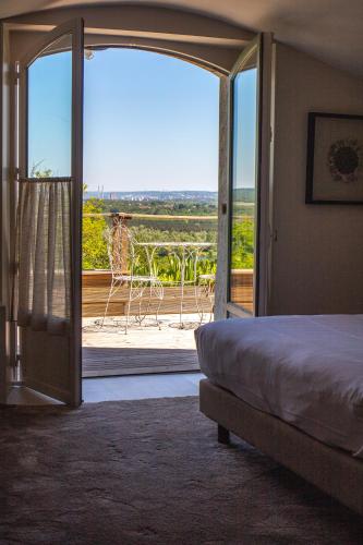 a bedroom with a bed and a sliding glass door at Domaine De La Corniche in Rolleboise