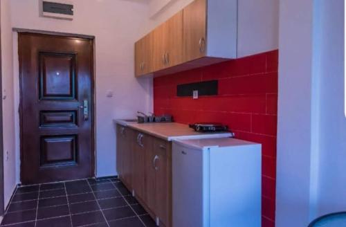uma cozinha com um frigorífico branco e uma parede vermelha em Apartmani Maša em Budva