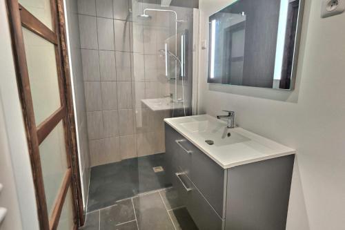 ein weißes Badezimmer mit einem Waschbecken und einem Spiegel in der Unterkunft Superbe, T2 élégant, Neuf, Parking in Gerde