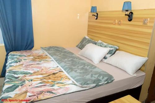 a bed in a room with a bedspread and pillows at MTA Lounge and Leisures in Enugu