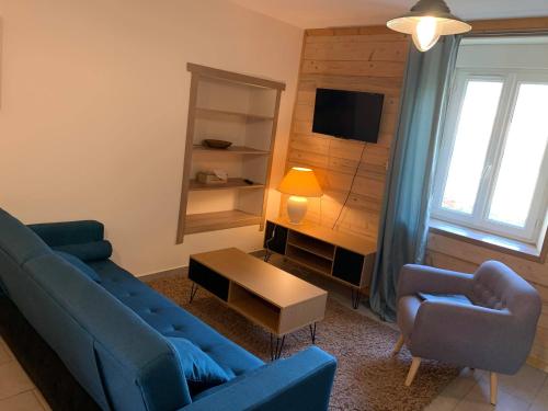 Una sala de estar con dos sofás azules y un televisor. en Gites des Casernes, en Saint-Christophe