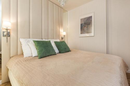 a bedroom with a large bed with two green pillows at LuxApart Gdańsk in Gdańsk