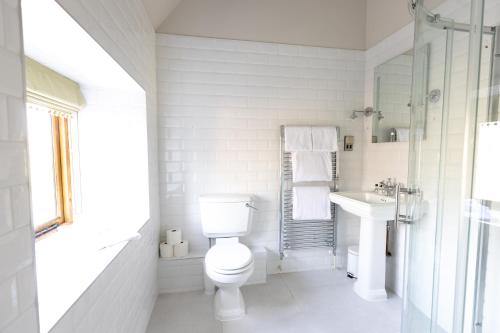 a white bathroom with a toilet and a sink at The Fox at Barrington in Burford