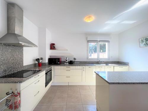 - une cuisine avec des placards blancs et des comptoirs en granit dans l'établissement Mare et Monti vue mer proche centre ville, à Propriano