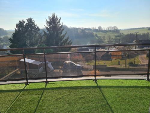 a balcony with a view of a car on the grass at Gite chalet Au Paradis d Eole in Villeparois