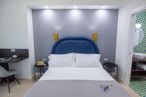 a bedroom with a bed with a blue head board at Mako Sorrento Suites in Sorrento