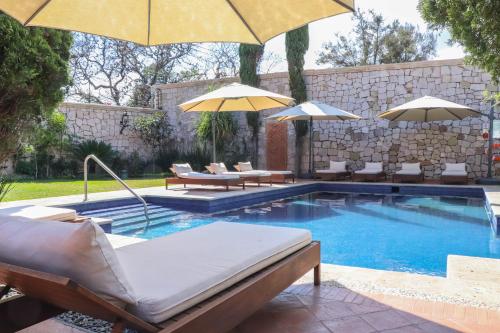 a swimming pool with chairs and umbrellas next to it at Gamma Morelia Vista Bella in Morelia