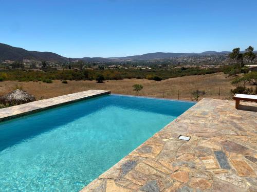 una piscina con un banco en un patio de piedra en Suites Nativo - Beautiful Vineyard & Valley View, en Valle de Guadalupe